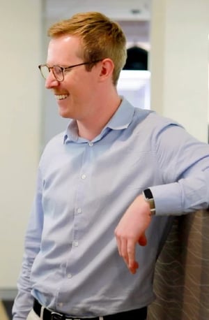 Altius Group man with glasses leans on desk