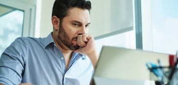 A man looking at a tablet screen, suffering workplace anxiety